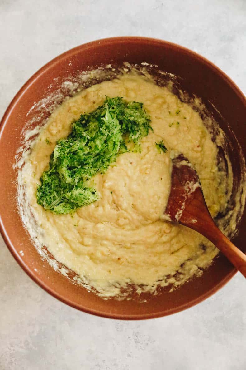 zucchini being folded into muffin batter.