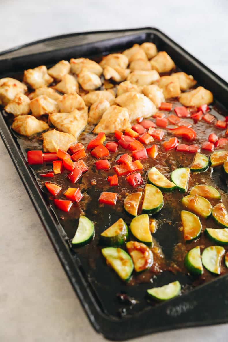 Baked chicken breast, bell pepper and zucchini in a pineapple sauce on a baking sheet.