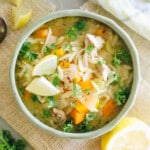 Lemon Chicken Orzo Soup in a green bowl with lemon slices.