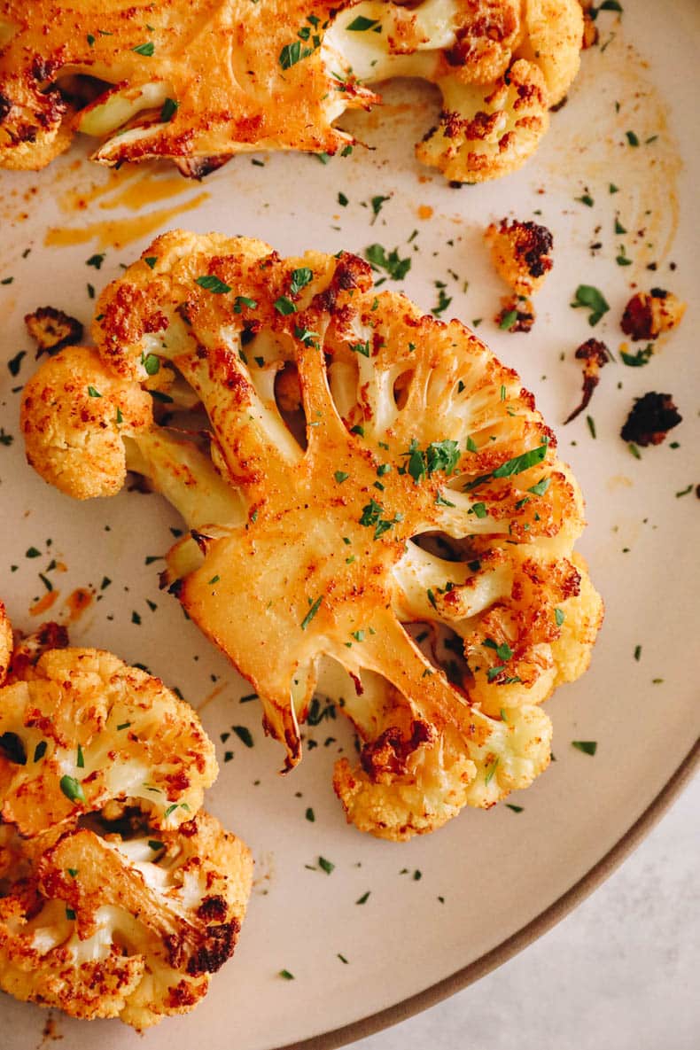 Upclose overhead image of cauliflower steak with chopped parsley.