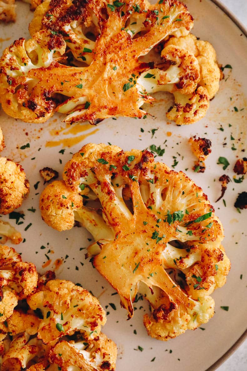 cauliflower steak recipe on a white plate with chopped parsley