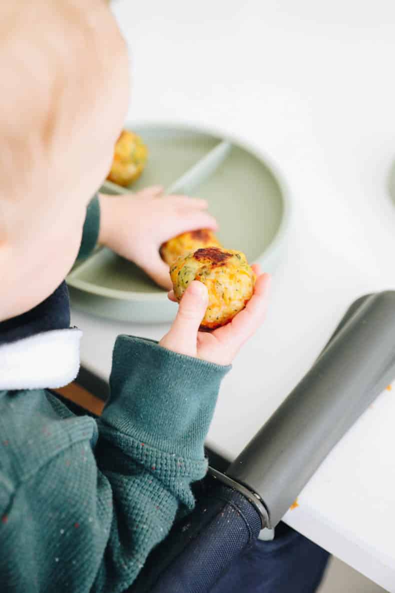 baby holding a chicken meatball.