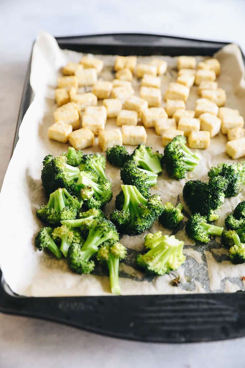 baked tofu and broccoli on a parchment lined sheet pan.