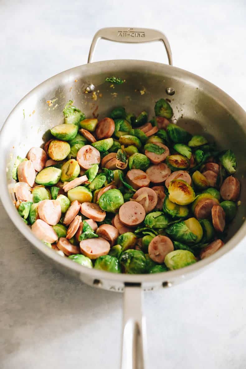 Chicken sausages and Brussels buds are cooked in a large pot.