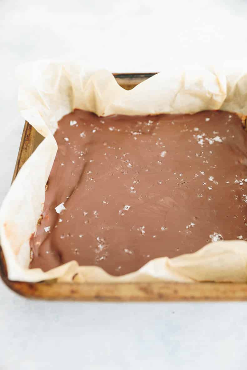 chocolate almond butter bars in a parchment lined baking pan with sprinkled sea salt.