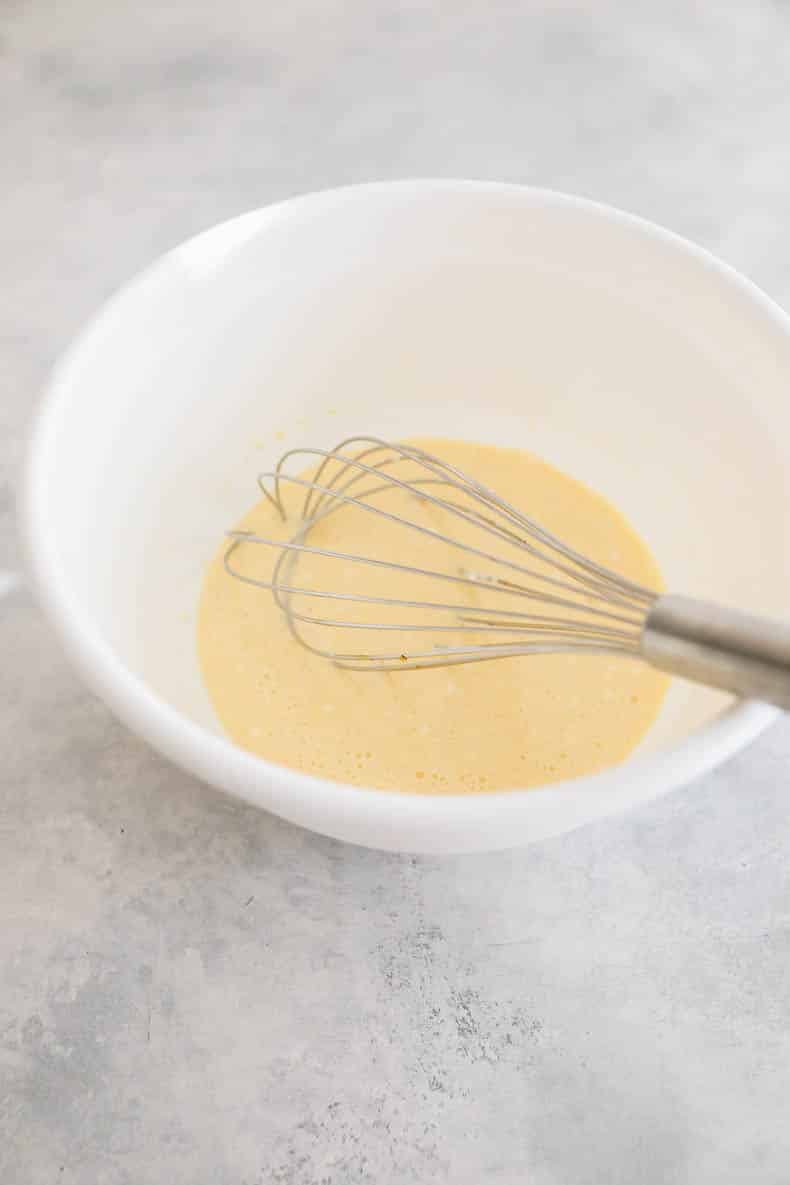 Wet pancake batter in a white bowl with a whisk