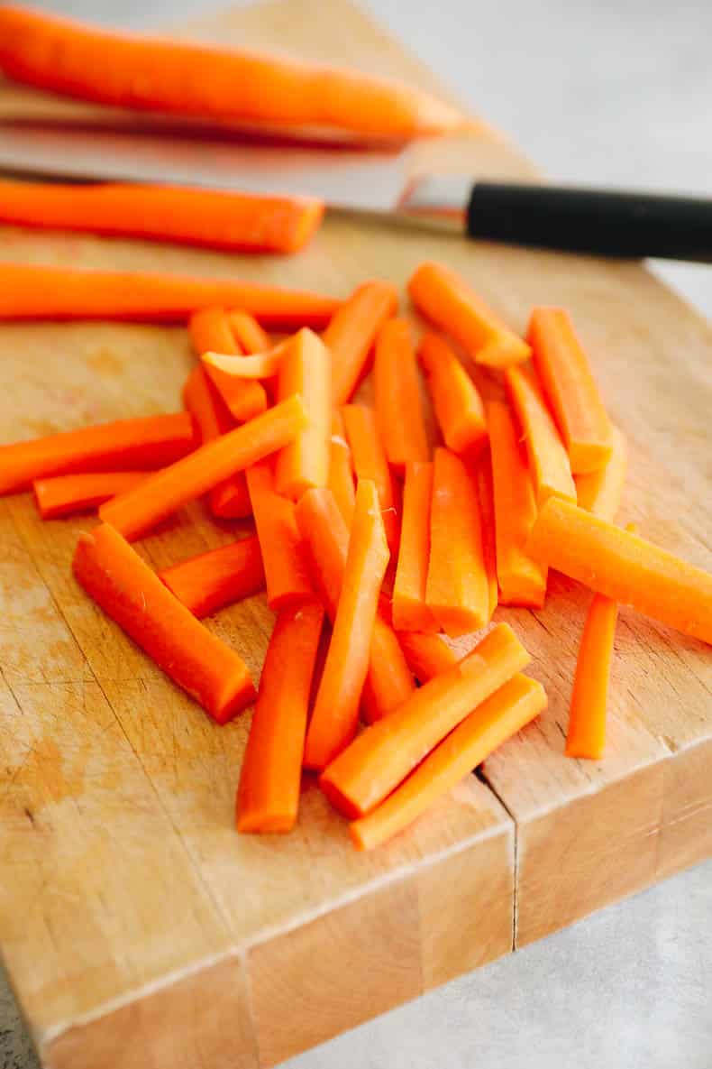 Carrots sliced into fries on a cutting board.