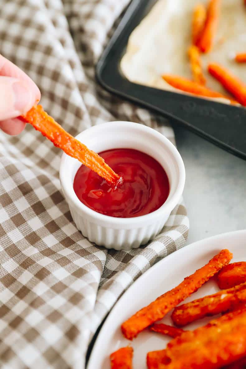 crispy carrot fry being dipped into ketchup.