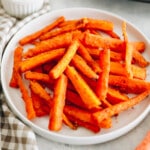 Crispy baked carrot fries on a white plate.