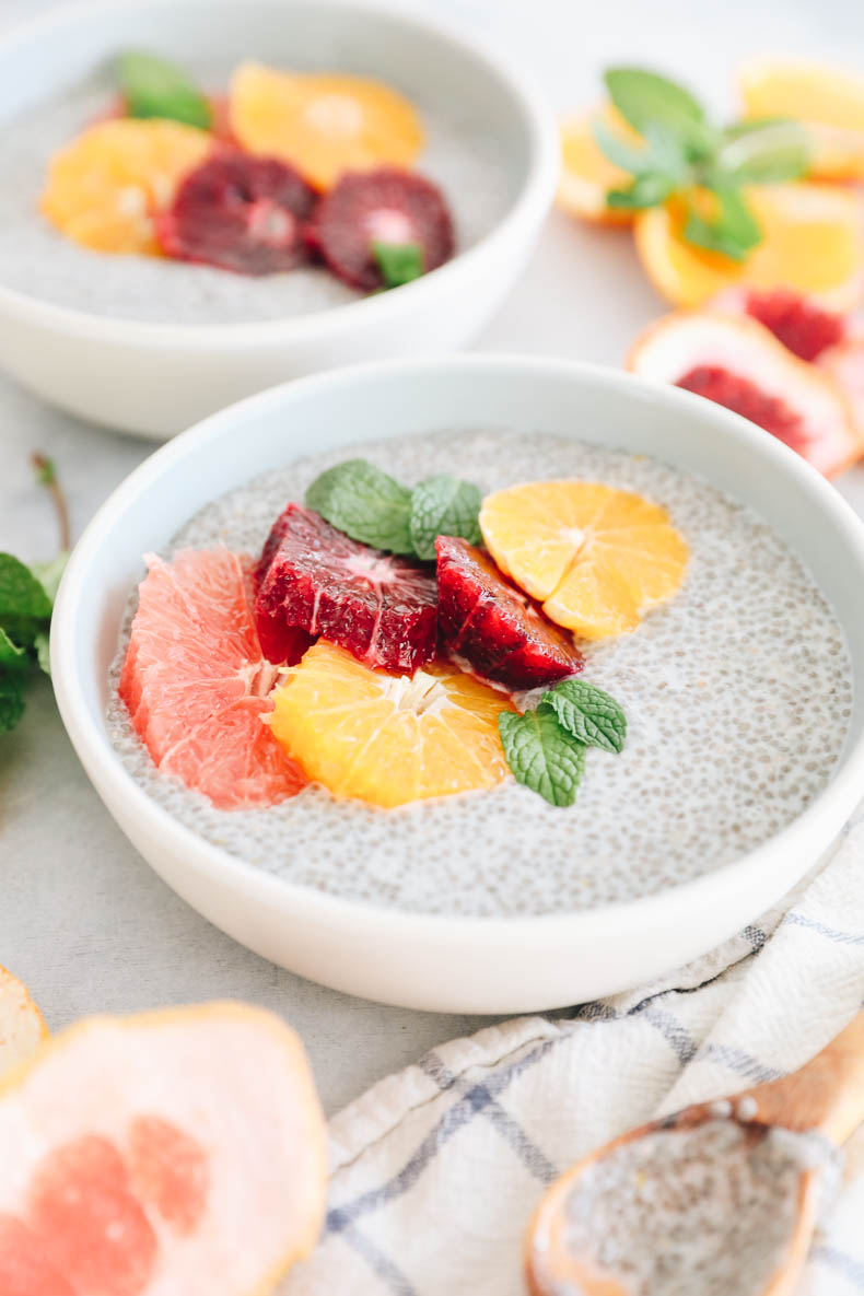 close up image of chia pudding in a blue and white bowl with grapefruit, blood orange and tangelo and mint leaves.