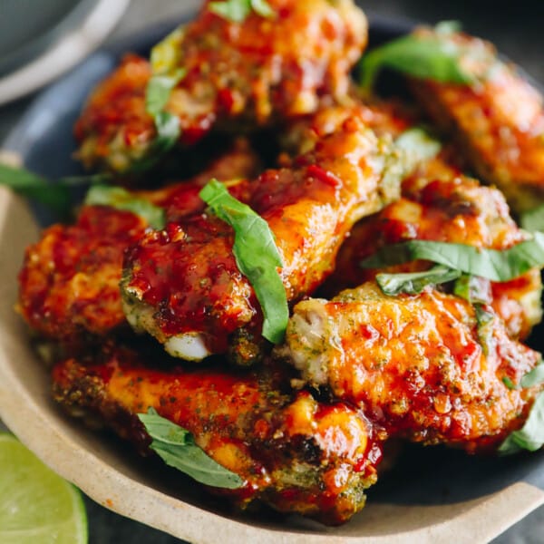 Baked thai chicken wings in a bowl with chopped thai basil.