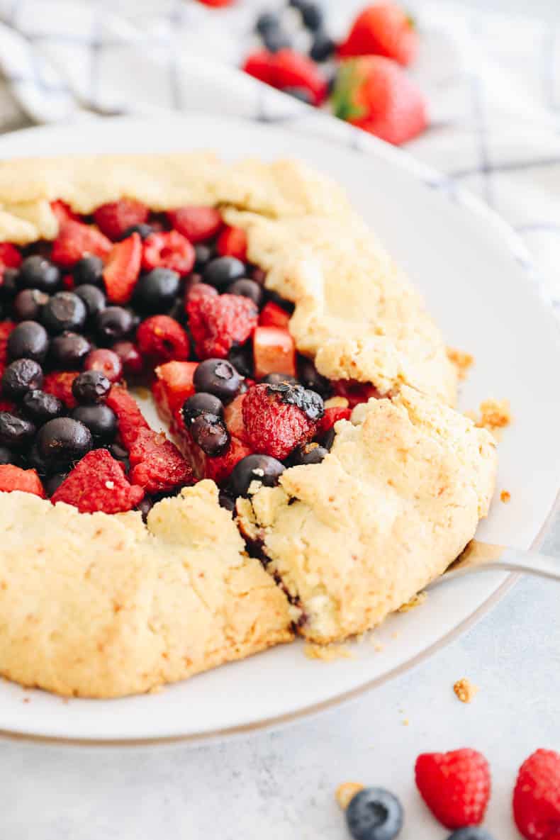 almond flour berry galette on a white plate with a pie cutter