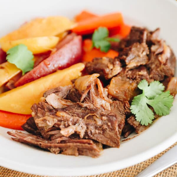 Close up of instant pot pot roast and veggies in a white shallow dish.