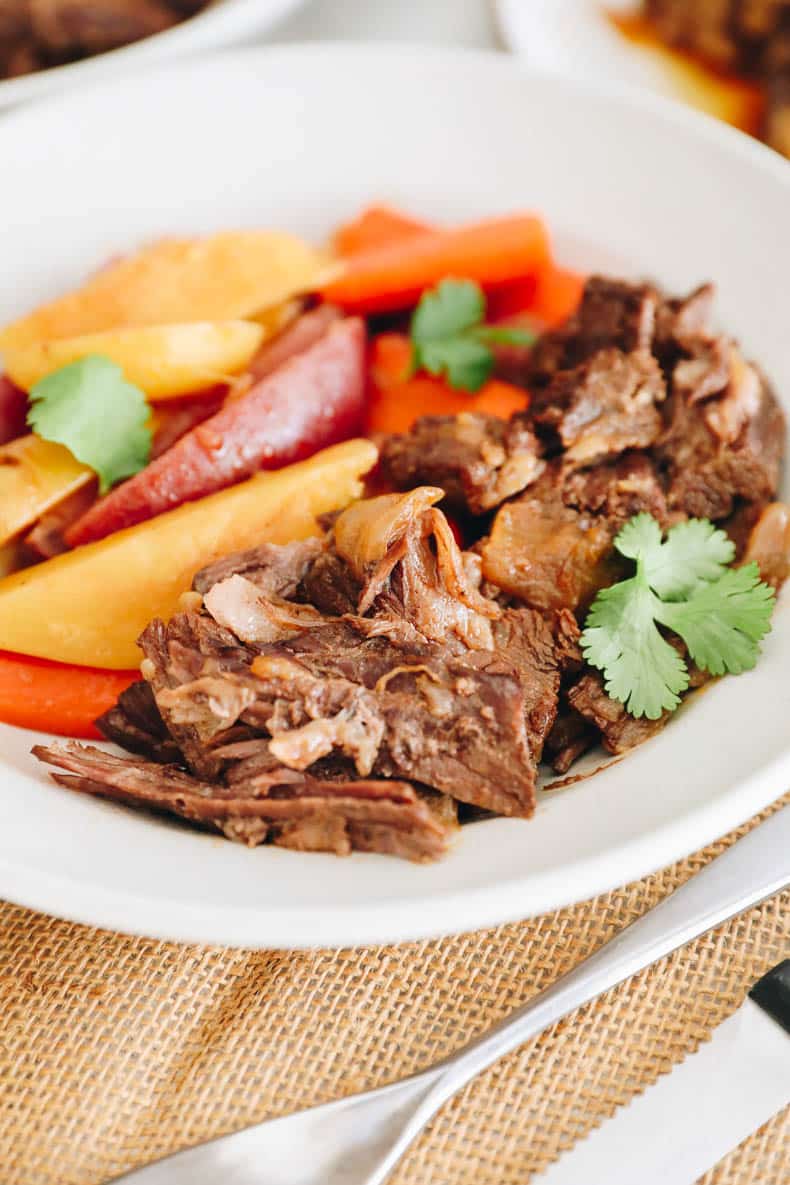 Instant pot chuck roast with potatoes and carrots served in a white shallow bowl.