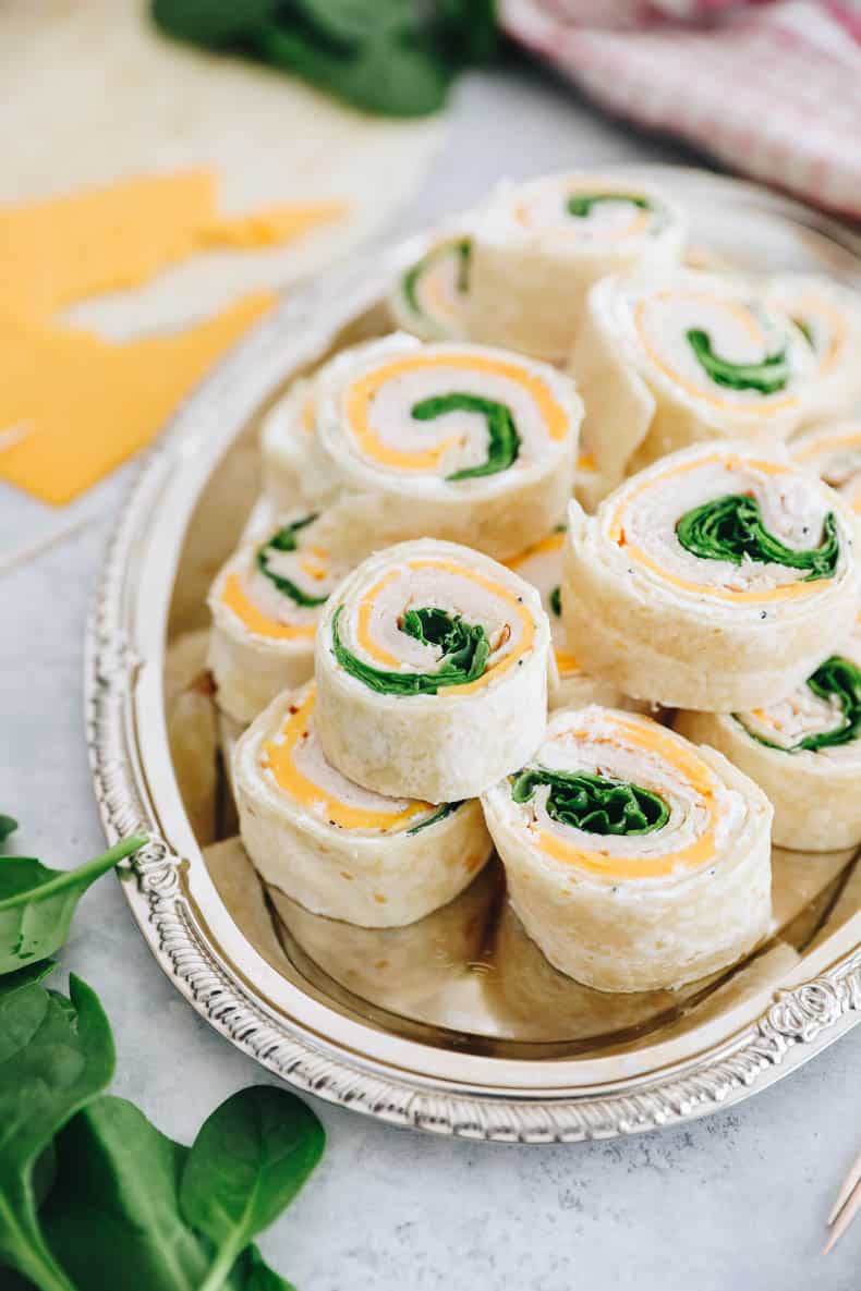 pinwheel sandwiches with turkey, cheese and spinach on a silver platter