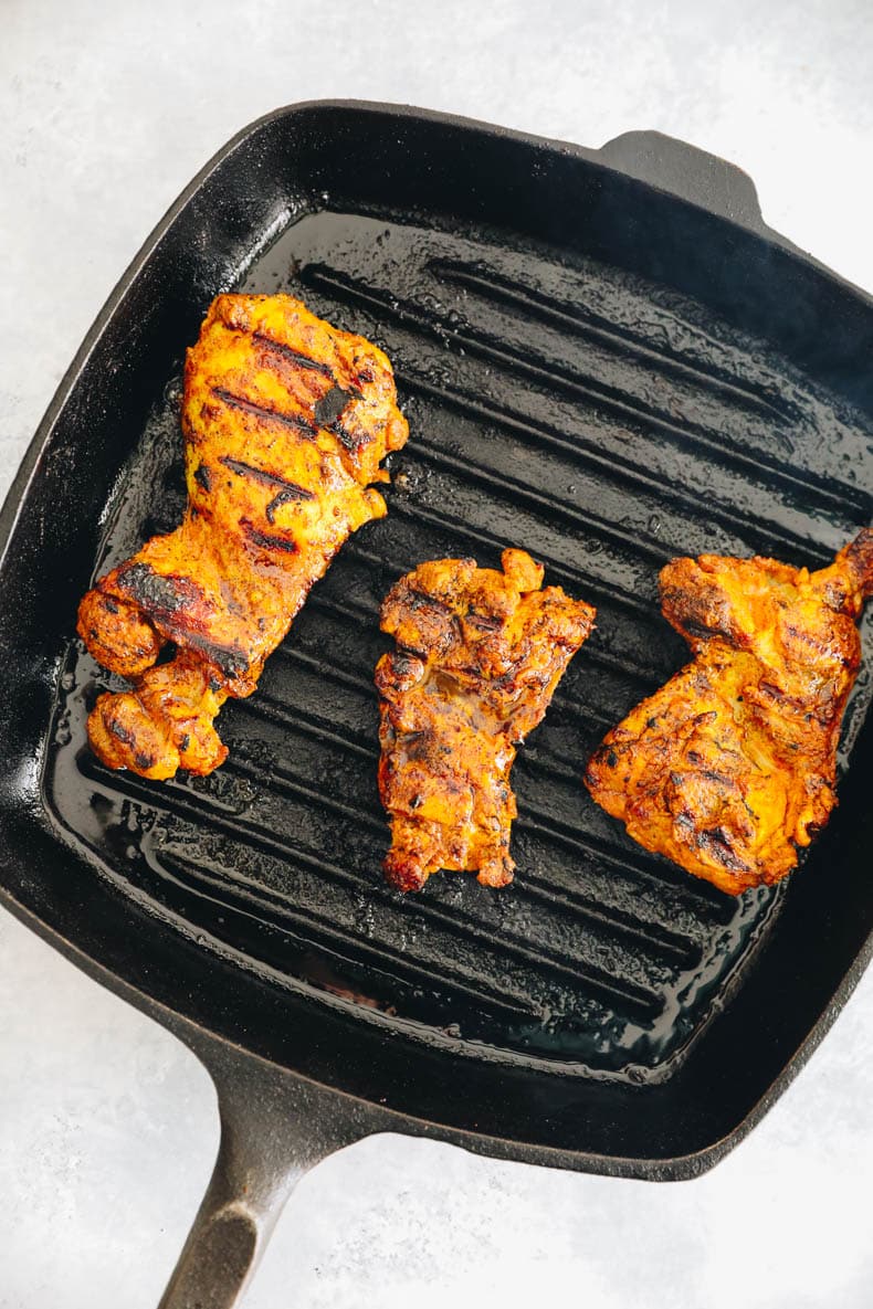 Grilled chicken thighs on a cast iron grill pan.